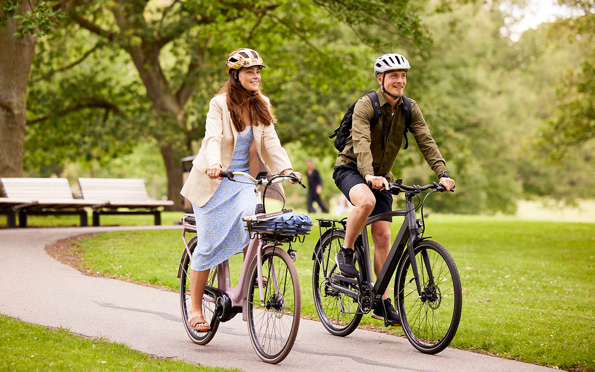 Ung Kvinde Og Mand Cykler På Elcykel Gennem Park